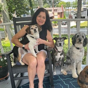 Woman with four dogs sitting on a porch, pet sitting service, outdoor pet care, Lakeside Pet Sitting.