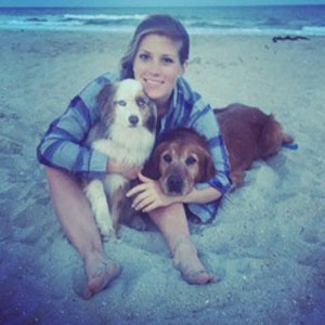 A woman sitting on the beach with two dogs, enjoying a sunny day. Perfect for pet sitting, dog care,.