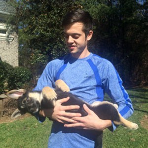 Young man holding a playful puppy outdoors, pet sitting service in Lakeside.