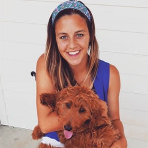 Happy woman with her adorable brown poodle dog.