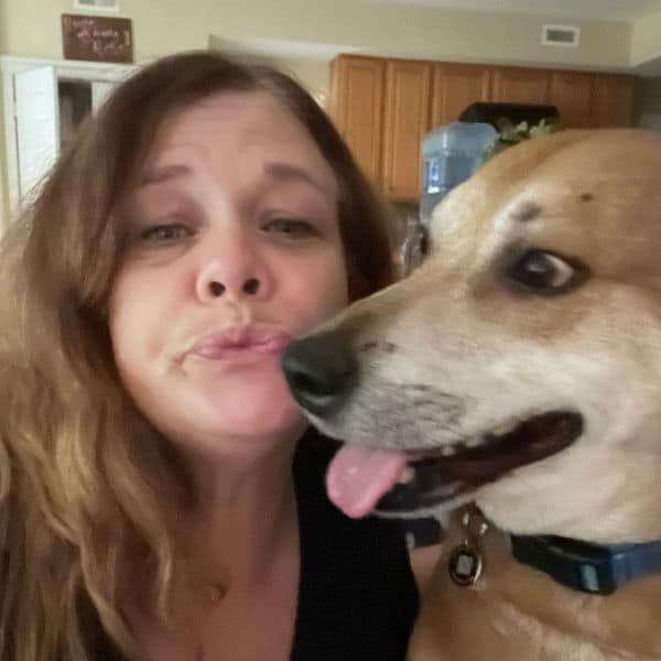 Woman making a funny face with her dog indoors, showcasing pet care and companionship.