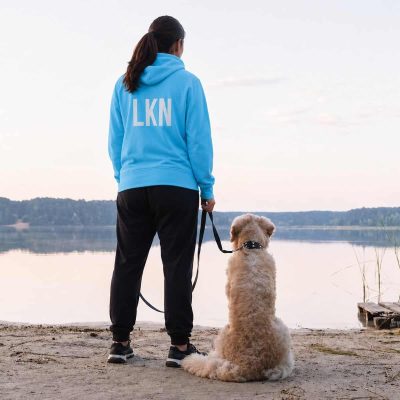 Pet sitter with dog by lake, offering professional pet sitting services near water.